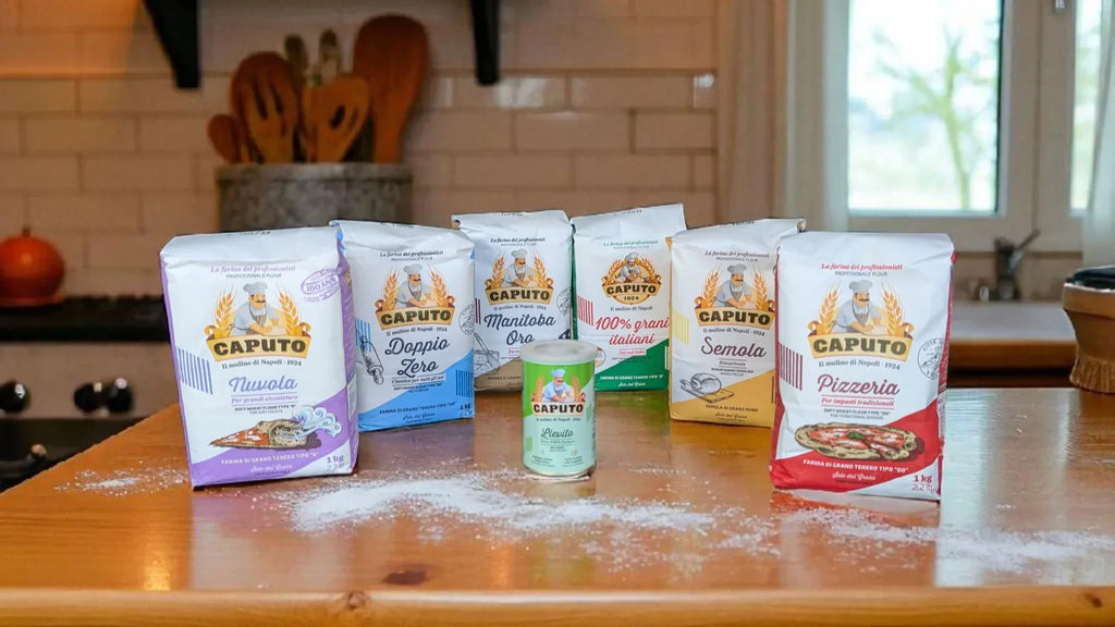 Assorted Caputo flour bags on a wooden kitchen counter, including Nuvola, 00, Manitoba Oro, Semola, 100% Italiano, and Pizzeria varieties.
